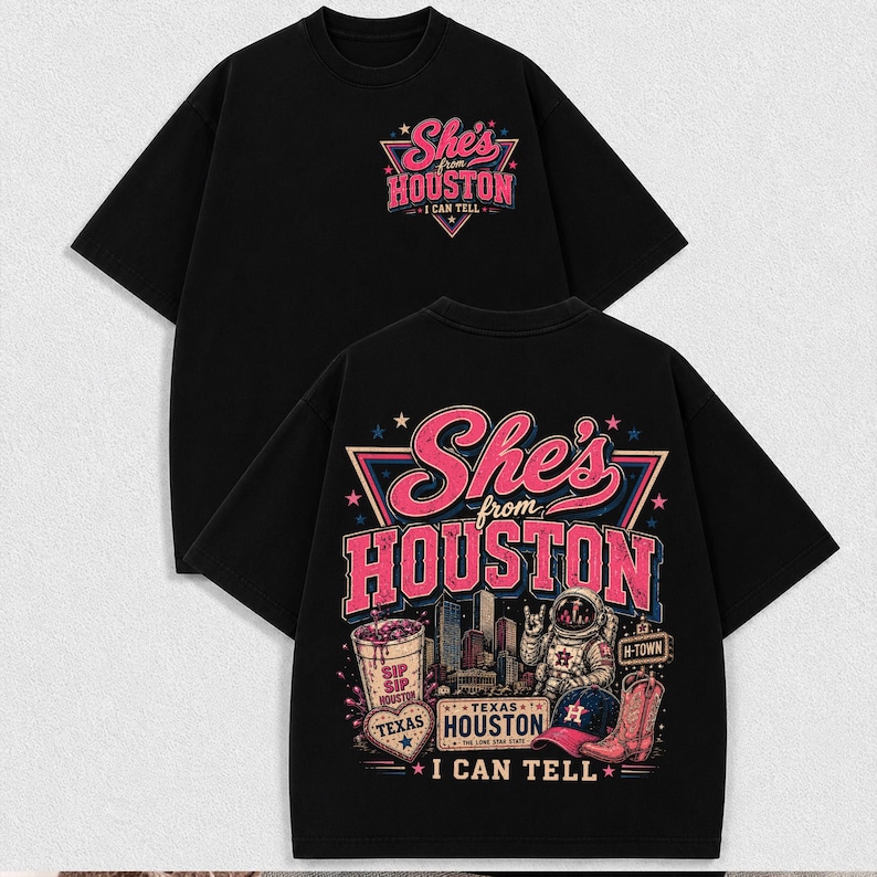 May include: A black short-sleeve t-shirt featuring a graphic design. The front displays the text She's from HOUSTON I CAN TELL. The back features a large illustration of an astronaut, a cowboy boot, a baseball cap, and a drink cup with the text She's from HOUSTON I CAN TELL.