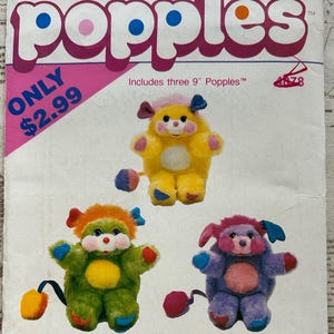 May include: A vintage pattern for Popples plush toys. The pattern features three colorful Popples, each approximately 9 inches tall, in yellow, green, and purple. The pattern includes the text "Popples" in large pink letters and the Butterick logo.