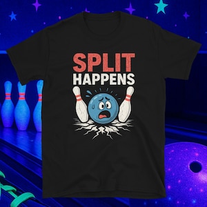 Può includere: T-shirt nera con la scritta "SPLIT HAPPENS" in rosso e bianco. La grafica presenta una palla da bowling blu con un'espressione preoccupata e due birilli bianchi. La maglietta è a maniche corte.