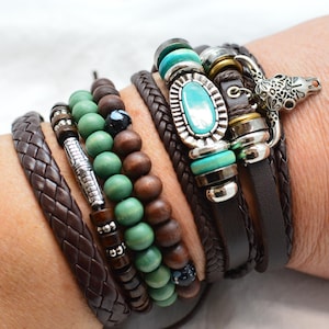 May include: A collection of bracelets in various styles and materials. Braided brown leather, wooden beads in green and brown, and bracelets with turquoise and silver accents. One bracelet features a silver animal charm.