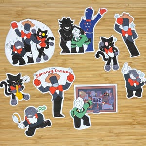 Puede incluir: Una colección de pegatinas coloridas con personajes de dibujos animados. Las pegatinas representan un gato negro con pajarita roja, una figura con traje y sombrero, y otros personajes únicos. Algunas pegatinas tienen el texto "Sensory Issues" y "MIKE".