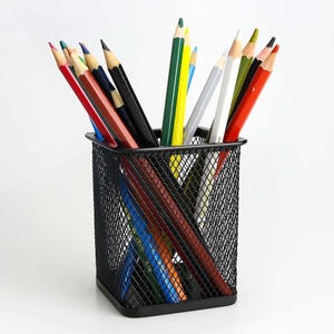 Könnte beinhalten: Ein schwarzer Stifthalter aus Netzstoff, gefüllt mit farbigen Bleistiften. Die Stifte sind in verschiedenen Farben wie Rot, Blau, Grün, Gelb, Schwarz und Weiß gehalten. Die Bleistifte sind gespitzt.