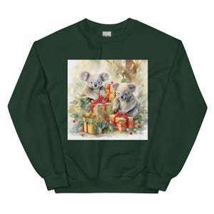 May include: Dark green sweatshirt featuring a watercolor print of two koalas with gifts. The koalas are surrounded by presents wrapped in red ribbons and greenery. The image has a soft, painterly quality, perfect for a cozy, festive look.