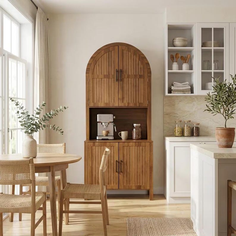 May include: A tall, arched wooden cabinet with vertical slats and dark metal handles, featuring two upper doors, an open middle shelf with a coffee machine, and two lower doors. The cabinet is positioned in a room with a wooden dining table and chairs.