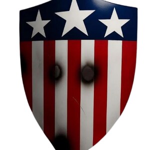K&ouml;nnte beinhalten: Ein Schild mit patriotischem Design, mit einem blauen Oberteil mit drei wei&szlig;en Sternen und rot-wei&szlig;en Streifen. Das Schild hat simulierte Einschussl&ouml;cher und ein abgenutztes Aussehen.