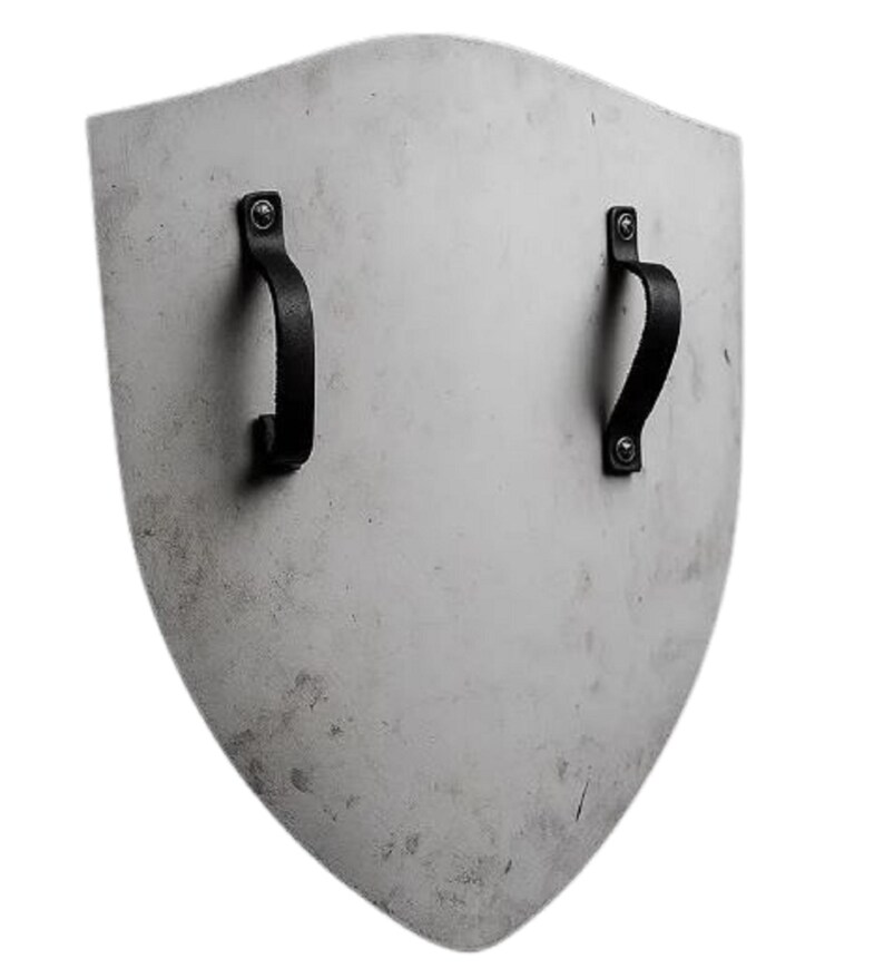 K&ouml;nnte beinhalten: Ein schildf&ouml;rmiges Objekt mit hellgrauer Oberfl&auml;che. Zwei schwarze Ledergriffe sind mit Nieten auf der R&uuml;ckseite befestigt. Das Schild hat ein leicht abgenutztes Aussehen, was auf Alter oder Gebrauch hindeutet.