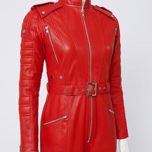 K&ouml;nnte beinhalten: Ein leuchtend roter Leder-Overall mit Stehkragen und Frontrei&szlig;verschluss. Der Overall hat einen G&uuml;rtel in der Taille, mehrere Rei&szlig;verschlusstaschen und Steppdetails an Schultern und &Auml;rmeln. Das Design ist schlicht und modern.