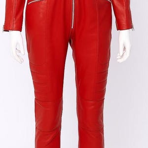 K&ouml;nnte beinhalten: Ein leuchtend roter Leder-Overall mit G&uuml;rtel und silbernen Rei&szlig;verschl&uuml;ssen. Das lang&auml;rmlige Kleidungsst&uuml;ck hat eine Steppung an Beinen und Schultern. Der Overall wird auf einer Schaufensterpuppe pr&auml;sentiert.