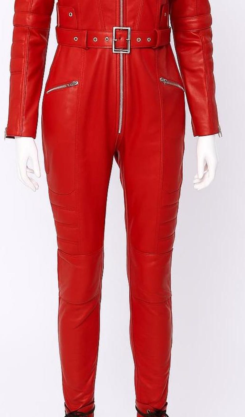 K&ouml;nnte beinhalten: Ein leuchtend roter Leder-Overall mit G&uuml;rtel und silbernen Rei&szlig;verschl&uuml;ssen. Das lang&auml;rmlige Kleidungsst&uuml;ck hat eine Steppung an Beinen und Schultern. Der Overall wird auf einer Schaufensterpuppe pr&auml;sentiert.