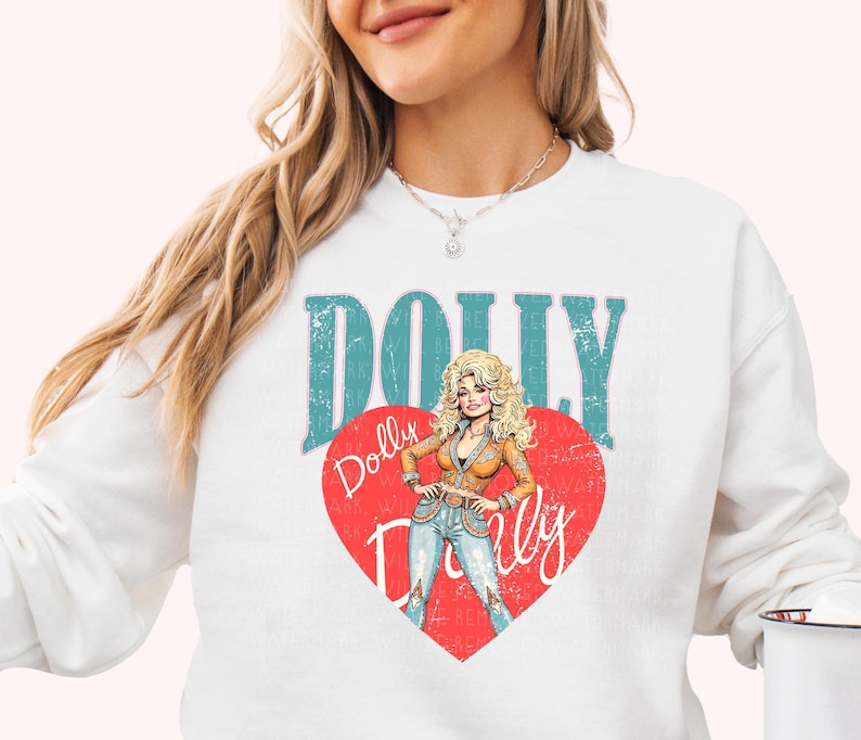 A woman wearing a white sweatshirt with a graphic design featuring a cartoon illustration of a blonde woman with curly hair and the word "Dolly" written on it.