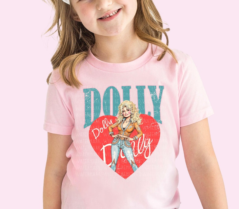 A young girl wearing a pink t-shirt with a graphic of a woman and the text "Dolly Dolly" printed on it.