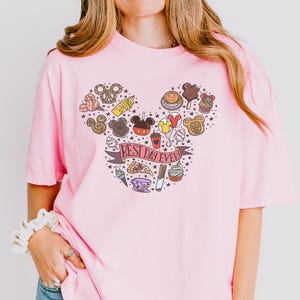 A woman wearing a pink t-shirt with a Mickey Mouse design and various Disney-themed items.