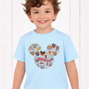 A young boy wearing a light blue t-shirt with a Mickey Mouse design and various Disney-themed icons.