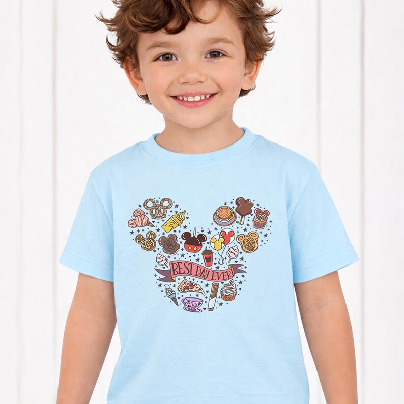 A young boy wearing a light blue t-shirt with a Mickey Mouse design and various Disney-themed icons.