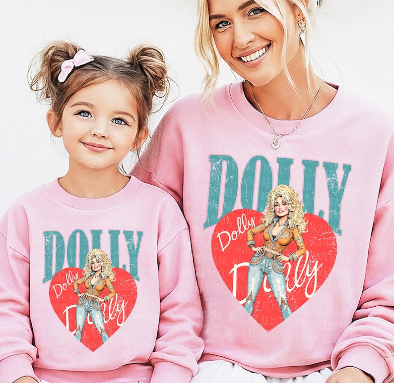 A young girl and an adult woman wearing matching pink sweatshirts with the word "Dolly" printed on them.