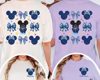 May include: Two short-sleeve t-shirts, one cream and one light purple, featuring a back print of navy blue Mickey Mouse silhouettes, blue bows, and cruise ship icons. The front chest area displays a single navy blue Mickey silhouette with a bow.