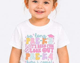 May include: A white t-shirt with the text "so long PRE-K3, it's been fun, look out PRE-K4, here I come!" in pastel colors. The shirt has a graduation cap graphic. The shirt is worn by a young child.