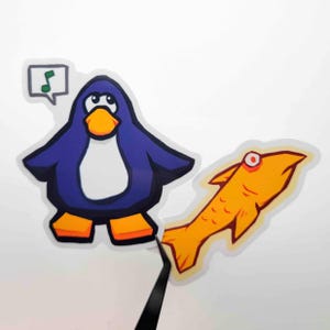 May include: A cartoon sticker set featuring a blue penguin with an orange beak and feet, and a yellow fish with a red eye. The penguin has a musical note speech bubble. The sticker set is on a white background.