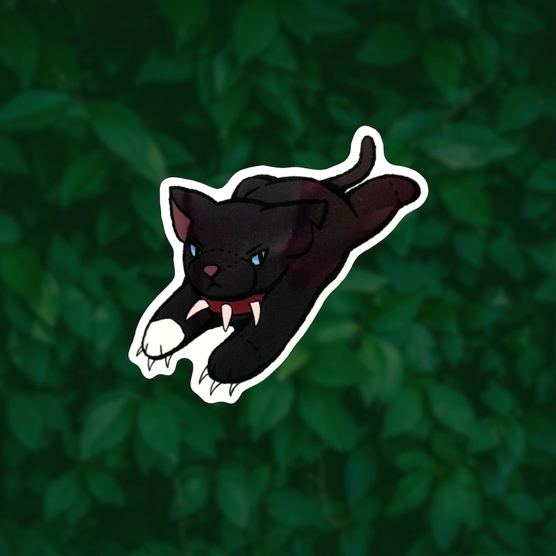 May include: A sticker illustration of a black cat in a pouncing position. The cat has blue eyes, a red collar with white spikes, and one white front paw. The design features a thick white border around the edges of the black feline figure.