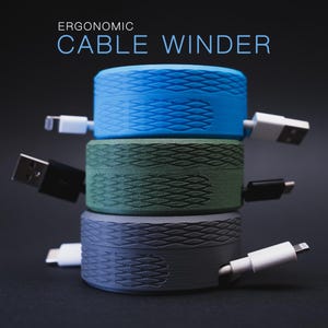 May include: Three-tiered cable winder in blue, green, and gray. Each winder has a textured surface and is connected to a cable. The text "ERGONOMIC CABLE WINDER" is at the top. The background is dark.