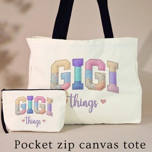 May include: Off-white canvas tote bag and matching zippered pouch. Both items feature the name "GIGI" in colorful patchwork letters, with the word "things" and a heart symbol. Black handles on the tote and a black zipper on the pouch.