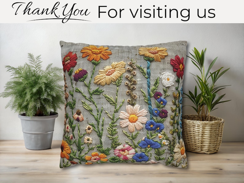 Pu&ograve; includere: Cuscino decorativo grigio ricamato con fiori colorati, tra cui fiori arancioni, gialli, rossi e blu. Il testo "Thank You For visiting us" &egrave; in alto. Il cuscino &egrave; posto davanti a un muro di colore chiaro.