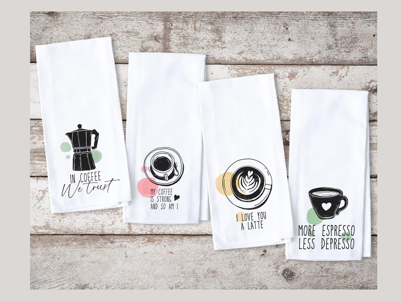 Może przedstawiać: Cztery białe ręczniki kuchenne z czarnymi wzorami o tematyce kawowej. Jeden ręcznik ma grafikę z kawiarką i napis "IN COFFEE We trust". Inne ręczniki przedstawiają grafiki filiżanek do kawy z napisami.