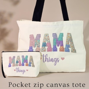 May include: A white canvas tote bag and matching pocket zip bag. The word "MAMA" is printed in colorful patchwork letters. The words "things" and a heart are printed in purple. Black handles on the tote bag.