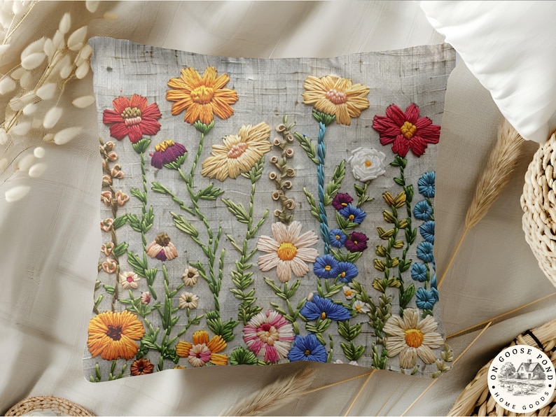 Pu&ograve; includere: Cuscino ricamato con un motivo floreale. Il cuscino presenta una variet&agrave; di fiori colorati, tra cui rossi, arancioni, gialli, rosa e blu, con steli e foglie verdi. I fiori sono ricamati su uno sfondo grigio.