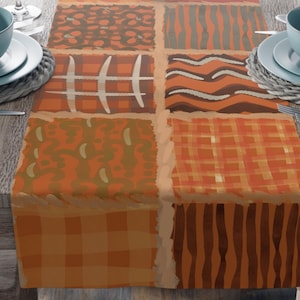 May include: A rectangular table runner featuring a patchwork design of six distinct squares in shades of orange, brown, and tan. The patterns include plaid, wavy lines, grid lines, and organic shapes, separated by a light tan border.
