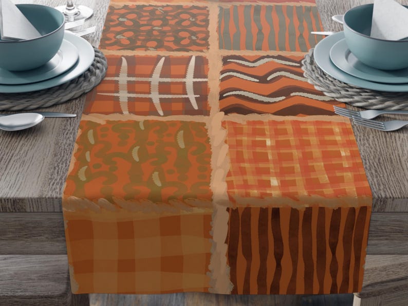 Op de afbeelding: Een rechthoekige tafelloper met een patchworkontwerp van zes verschillende vierkanten in tinten oranje, bruin en beige. De patronen omvatten ruiten, golvende lijnen, rasterlijnen en organische vormen, gescheiden door een lichte rand.