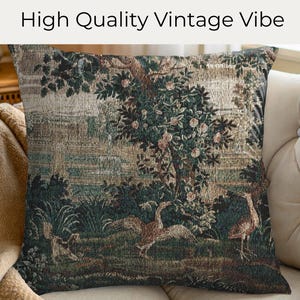 May include: Square cushion with a vintage tapestry design. The cushion features a detailed landscape scene with trees, birds, and foliage in shades of green, brown, and beige. The text "High Quality Vintage Vibe" is at the top.