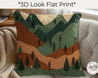 May include: A square throw pillow featuring a 3D look flat print of a mountain landscape. The design displays rolling hills in shades of forest green, sage, and terracotta, accented with dark green pine trees and a pale sun at the top center.