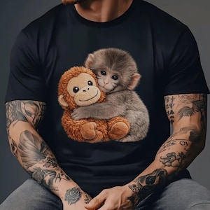 May include: Black t-shirt featuring a graphic of two hugging monkeys. One monkey is brown and plush, the other is gray and appears to be a real animal. The design is centered on the shirt.