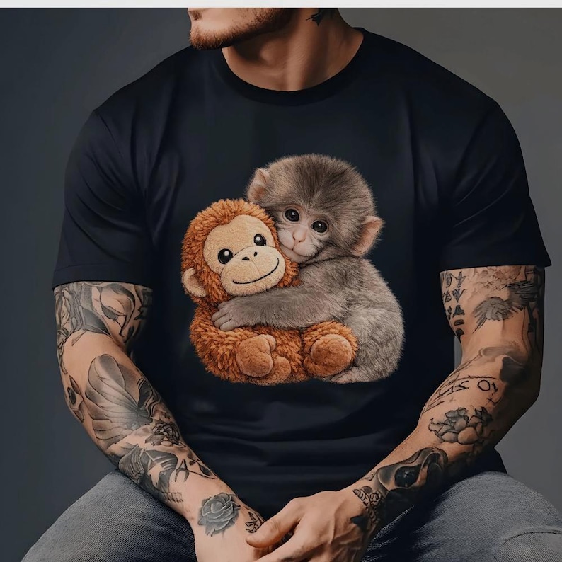 Puede incluir: Camiseta negra con un gr&aacute;fico de dos monos abraz&aacute;ndose. Uno es marr&oacute;n y de peluche, el otro es gris. La imagen est&aacute; centrada en la camiseta.