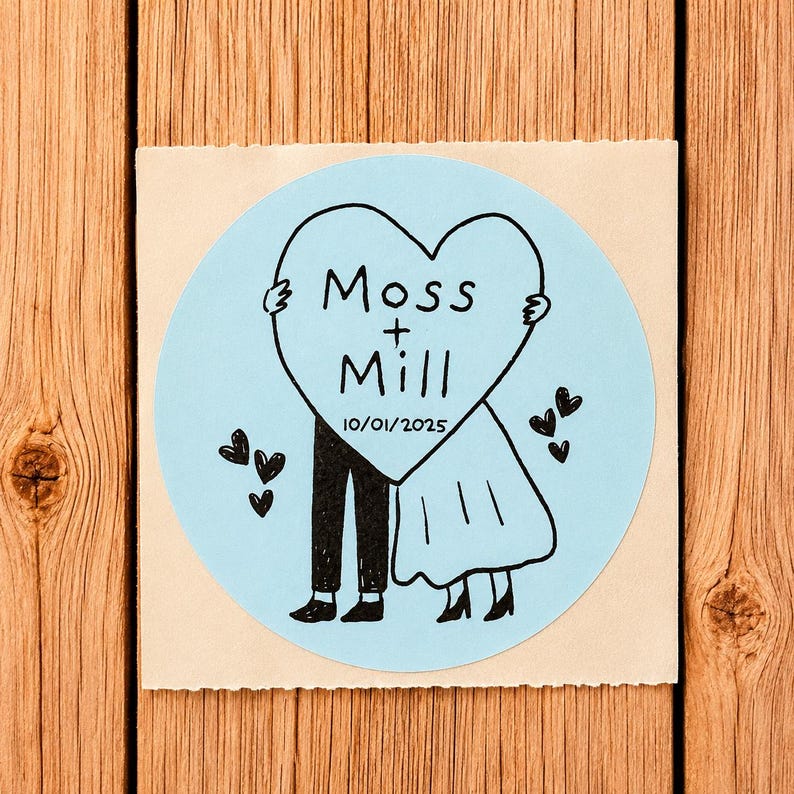 May include: A circular light blue sticker featuring a black ink illustration of two figures holding a large heart. The heart contains the text Moss + Mill and the date 10/01/2025. Small black hearts are scattered around the figures on the sticker.