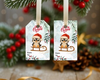 May include: Two Christmas gift tags with a penguin wearing a Santa hat on a sled. The tags have the text "Merry Christmas" and "From: To:" on a white background with snowflakes and greenery. The tags are hanging from a white ribbon.