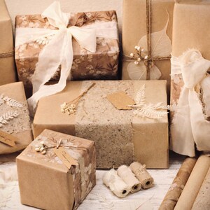 May include: An assortment of wrapped gifts in various sizes, adorned with natural elements. The packages are wrapped in brown paper and decorated with ribbons, dried flowers, and tags. The overall aesthetic is rustic and vintage.