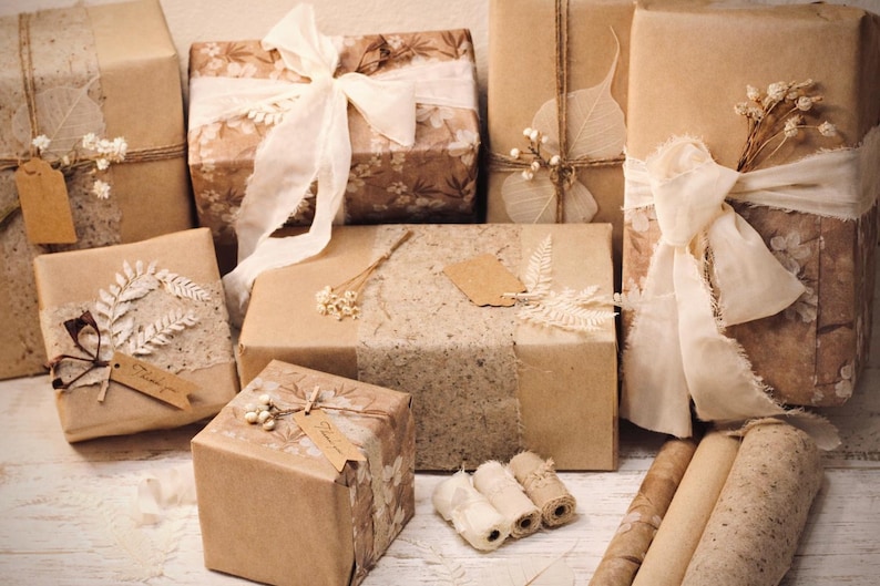 May include: An assortment of wrapped gifts in various sizes, adorned with natural elements. The packages are wrapped in brown paper and decorated with ribbons, dried flowers, and tags. The overall aesthetic is rustic and vintage.