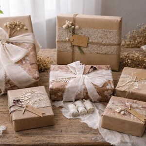 May include: Several gift boxes wrapped in brown paper, adorned with ribbons, lace, and dried flowers. Some boxes have tags. A pair of scissors and twine are also visible, suggesting a craft or gift-wrapping theme.