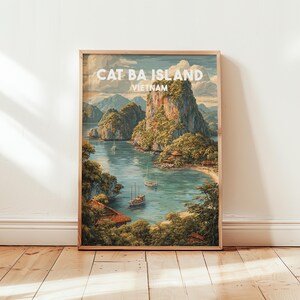 Op de afbeelding: Een ingelijste kunstdruk met een landschapsillustratie van het eiland Cat Ba in Vietnam. De scène toont kalkstenen kliffen, weelderige groene vegetatie, kalm blauw water en verschillende kleine boten. De tekst CAT BA ISLAND VIETNAM staat in het wit bovenaan.