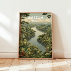 Op de afbeelding: Een ingelijste kunstafdruk met een schilderachtig uitzicht op de Amazone in Brazilië. Het kunstwerk toont weelderige groene bomen, een kronkelende rivier en de tekst "AMAZON BRAZIL" in het wit. De afdruk wordt gepresenteerd op een houten vloer.