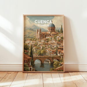 May include: Framed art print of Cuenca, Ecuador. The artwork depicts a picturesque cityscape with a domed cathedral, a stone bridge over a river, and buildings with red-tiled roofs. The text "CUENCA ECUADOR" is at the top of the print.