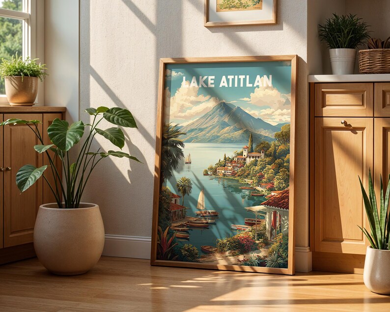 May include: A framed art print depicting Lake Atitlan, showcasing a colourful landscape with a mountain, lake, and village. The print is in a wooden frame and leans against a wall. The scene is illuminated by sunlight, with sailboats on the water.