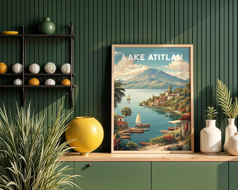May include: A framed print of Lake Atitlan, depicting a tranquil lake scene with sailboats, a mountain backdrop, and a village. The print has a light wood frame and is displayed on a green cabinet. The text "LAKE ATITLAN" is at the top.