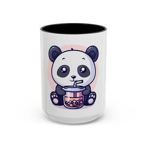 Op de afbeelding: Witte keramische mok met een zwarte binnenkant met een cartoon panda die een bubble tea vasthoudt. De panda is zwart en wit met een roze cirkel achtergrond. De mok is een standaard maat.