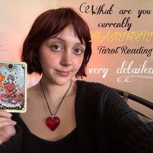 May include: A person holding a tarot card with a detailed illustration. The card features a figure in red and white attire. Text on the image reads "What are you currently MANIFESTING? Tarot Reading very detailed."
