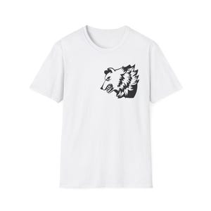 Puede incluir: Camiseta blanca con un dibujo negro de la cabeza de un oso, mostrando los dientes y los detalles del pelaje. El gráfico del oso está colocado en el lado izquierdo del pecho. La camiseta tiene mangas cortas y cuello redondo.
