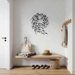 May include: A modern entryway with a wooden bench, a woven basket, and a metal wall art piece depicting a school of fish. A beige tote bag, a straw hat, and a coat hang on the wall. The floor is made of wood.