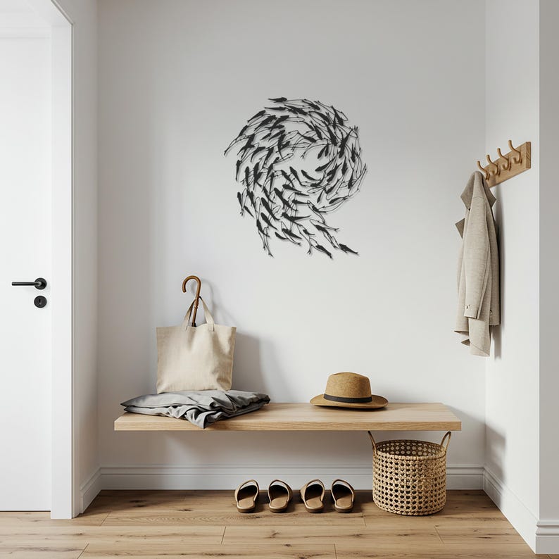May include: A modern entryway with a wooden bench, a woven basket, and a metal wall art piece depicting a school of fish. A beige tote bag, a straw hat, and a coat hang on the wall. The floor is made of wood.